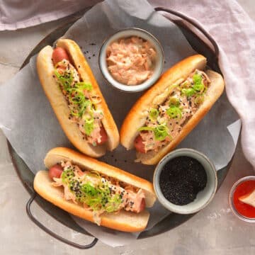 Kimchi hot dogs with small bowls of toppings on serving tray.
