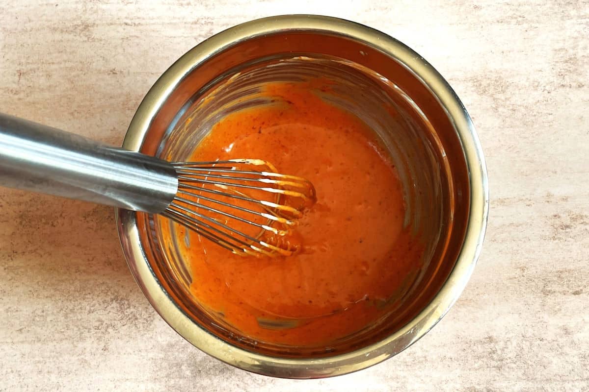 Gochujang mayo in bowl with whisk.