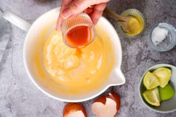Kimchi brine pouring into homemade mayo.