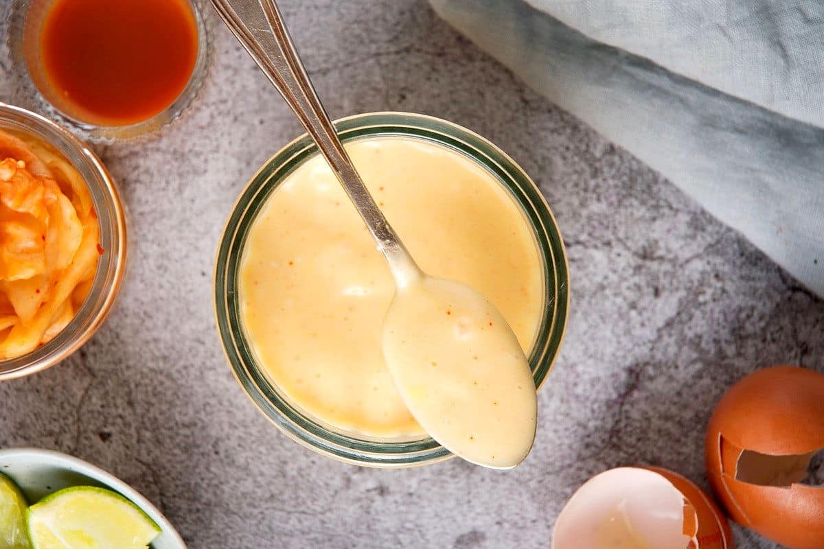 Kimchi mayo in jar and on metal spoon.