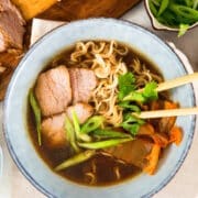 Kimchi ramen noodle soup in bowl with wooden chopsticks.
