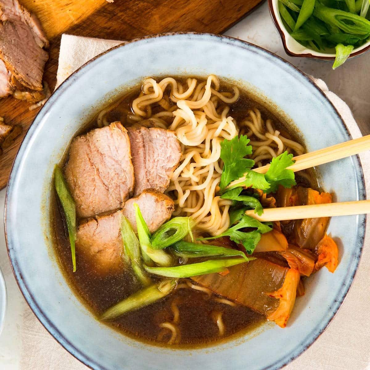 Kimchi ramen noodle soup in bowl with wooden chopsticks.