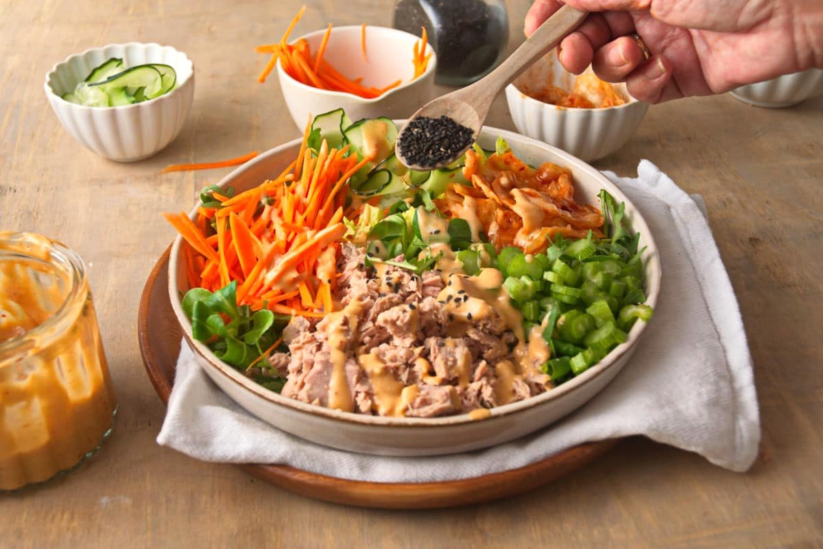 Kimchi salad on a plate with black sesame seeds on a spoon.