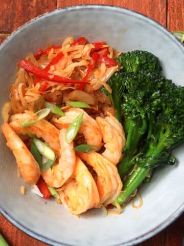Kimchi shrimp stir fry in bowl on wooden background.