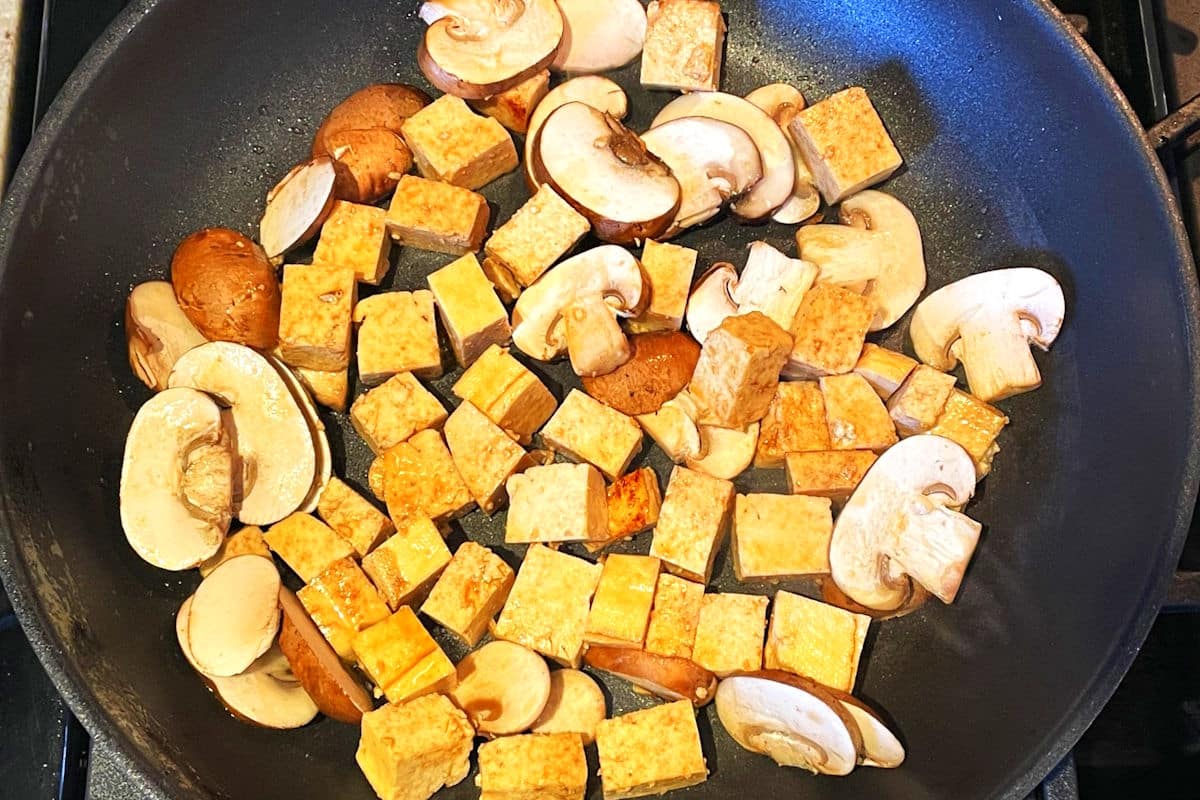 Tofu and cremini mushrooms in frying pan.