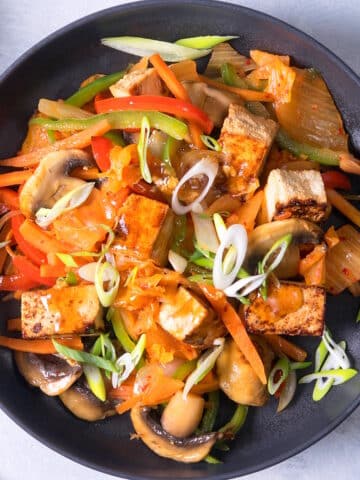 Kimchi and tofu stir fry in black dish.