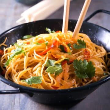 Kimchi udon in a bowl with chop sticks.