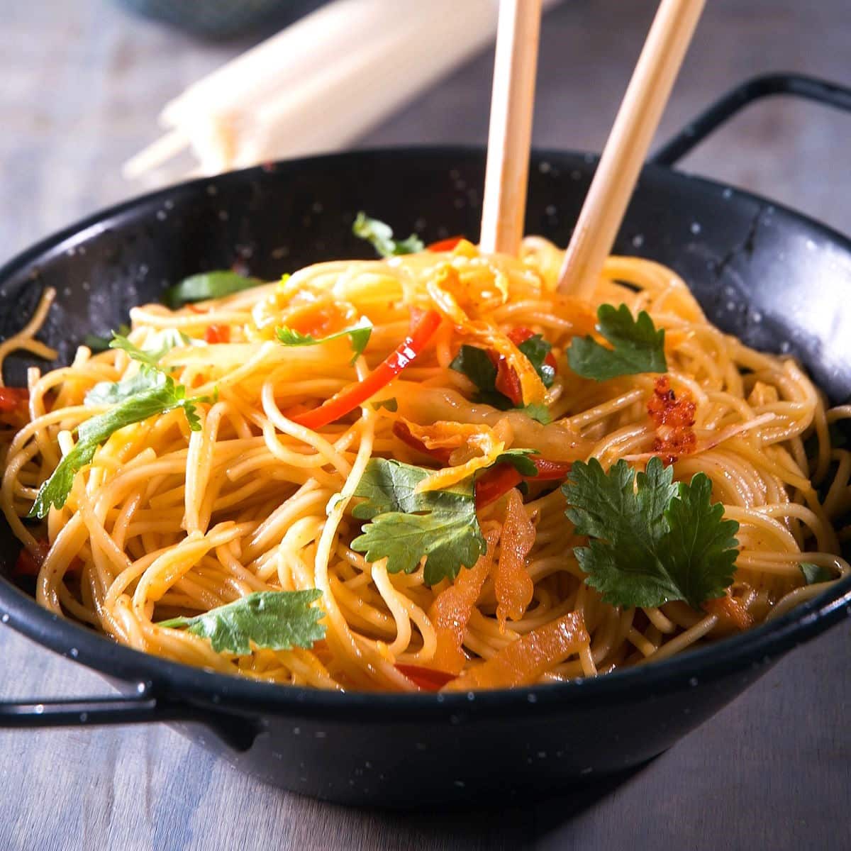 Kimchi udon in a bowl with chop sticks.