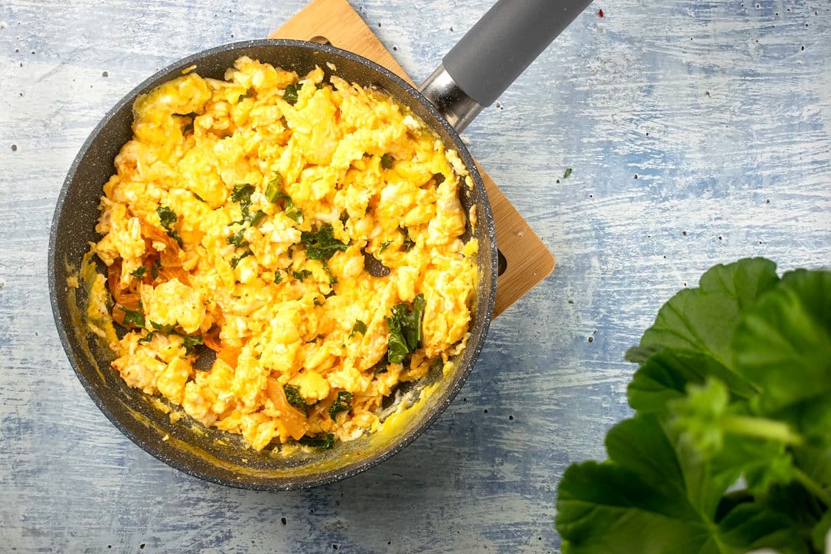 Korean kimchi scrambled eggs in pan on blue background.