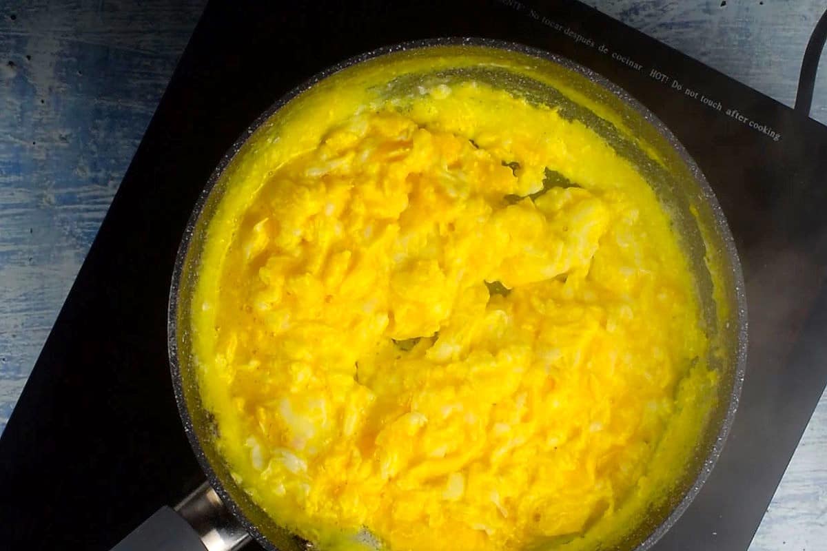 Scrambled eggs cooking in pan.