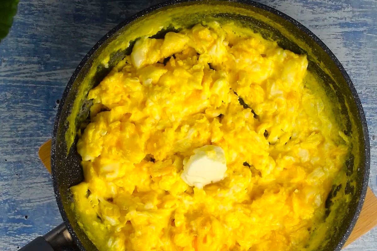 Scrambled eggs in pan with dollop of sour cream.