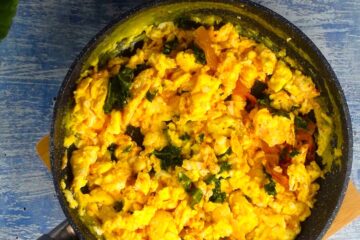 Kimchi scrambled eggs in pan with kale.