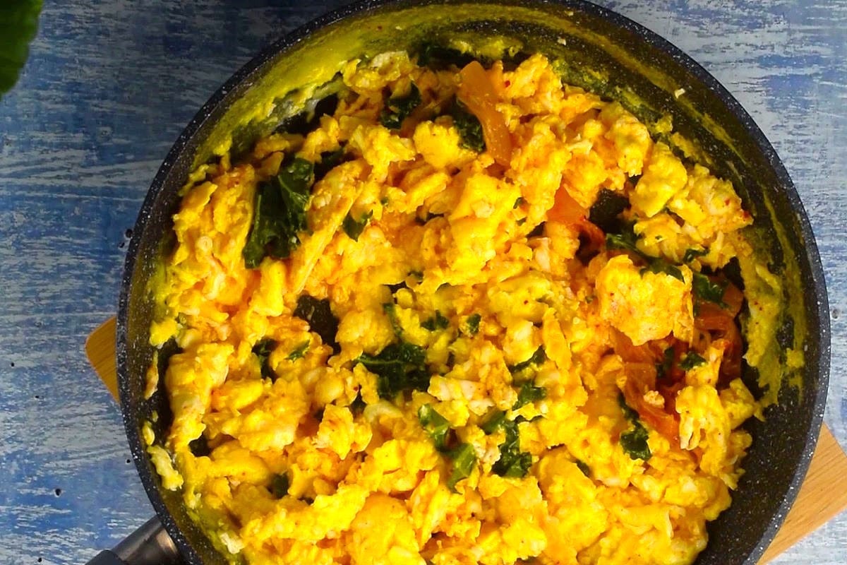 Kimchi scrambled eggs in pan with kale.