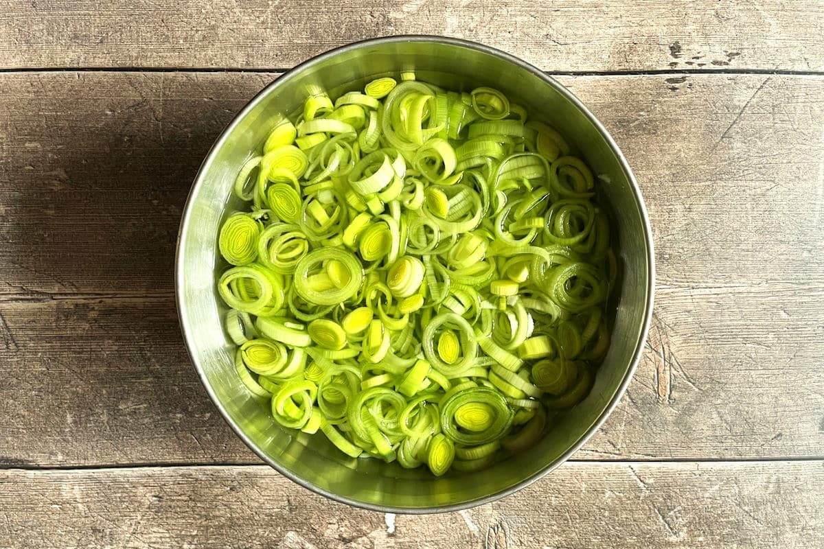 Sliced leeks in bowl of cold water.