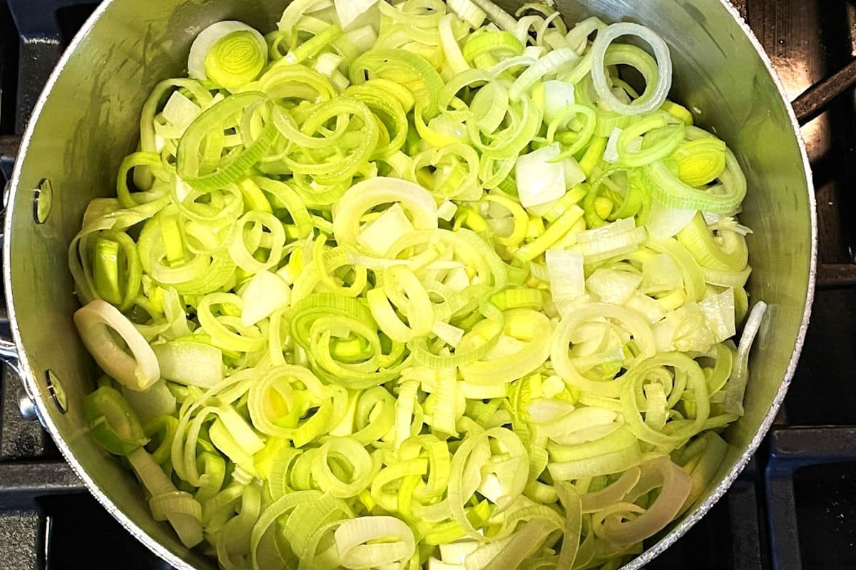 Sliced leeks and onions in pot.