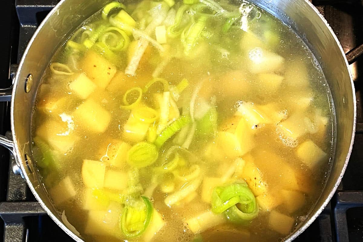 Potato leek soup cooking in pot.