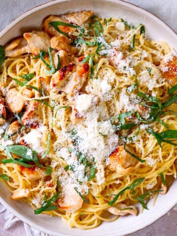 Lemon basil pasta with chicken and Parmesan cheese on plate.