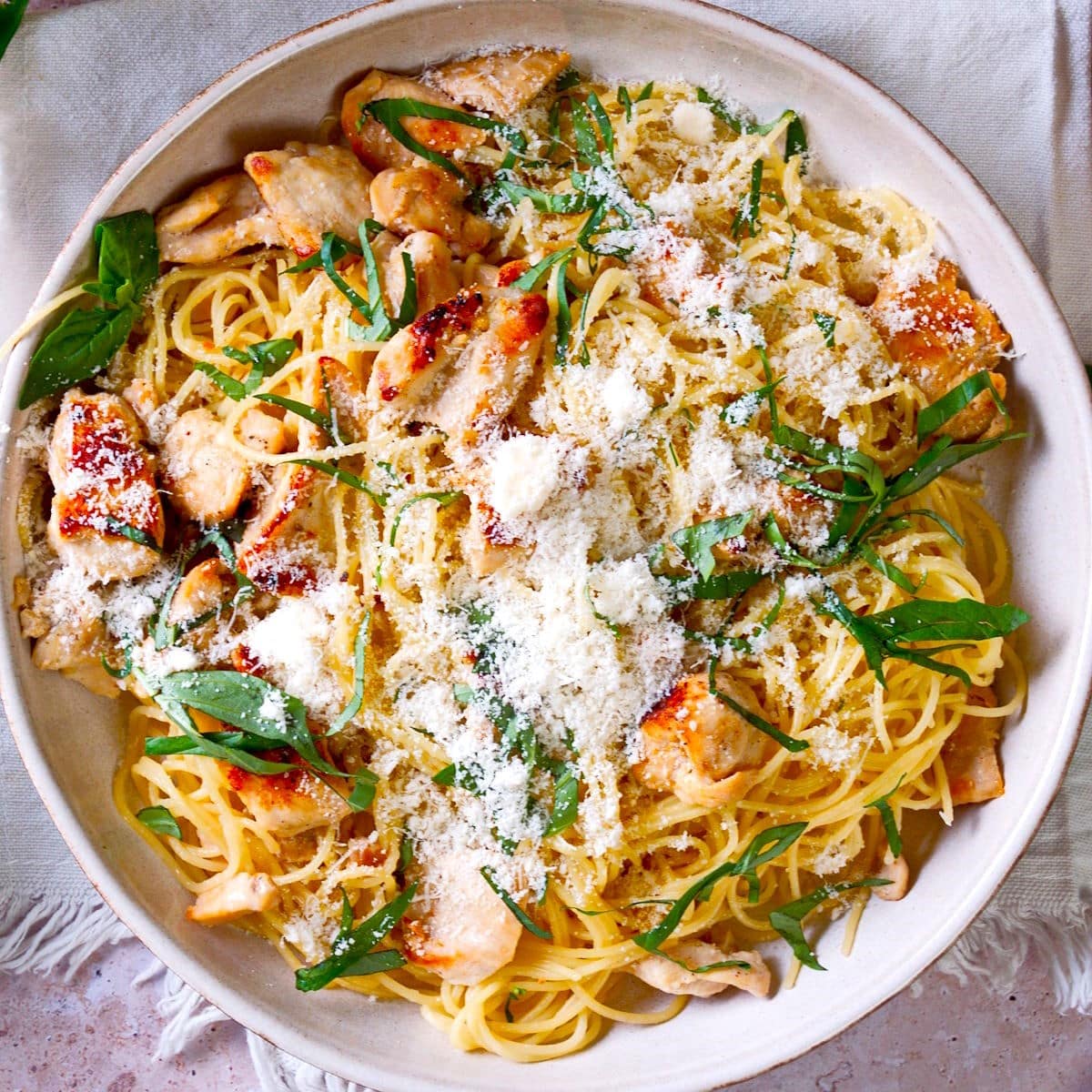 Lemon basil pasta with chicken and Parmesan cheese on plate.