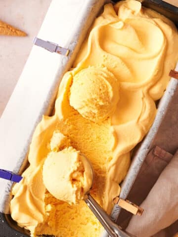 Mac and cheese ice cream in loaf pan with ice cream scoop.