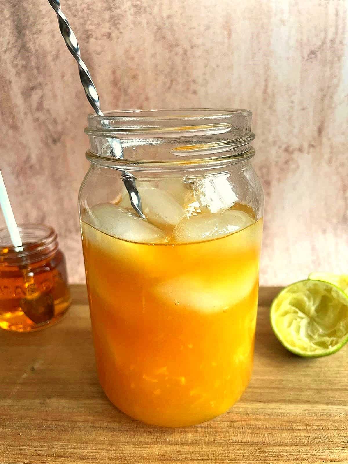 Mango ginger cocktail getting stirred with bar spoon.