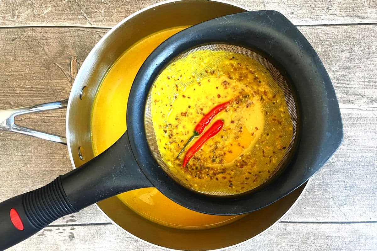 Mango soup strained through mesh strainer into pot.