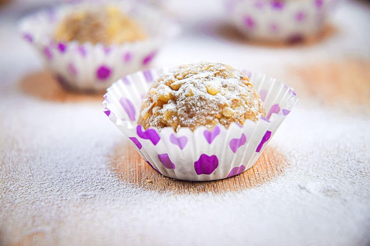 Marzipan ball dusted in icing sugar in white and purple baking cup.