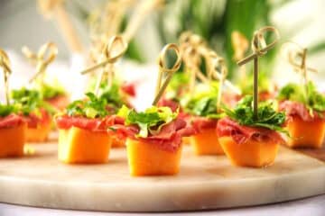 Melon prosciutto skewers with toothpicks on serving tray.