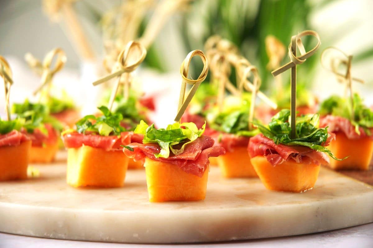 Melon prosciutto skewers with toothpicks on serving tray.