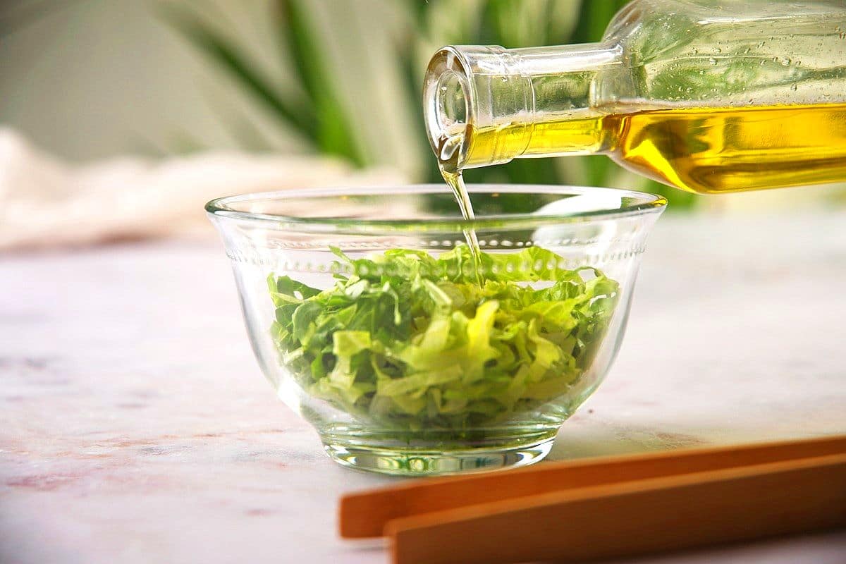 Diced greens in bowl and bottle of olive oil.