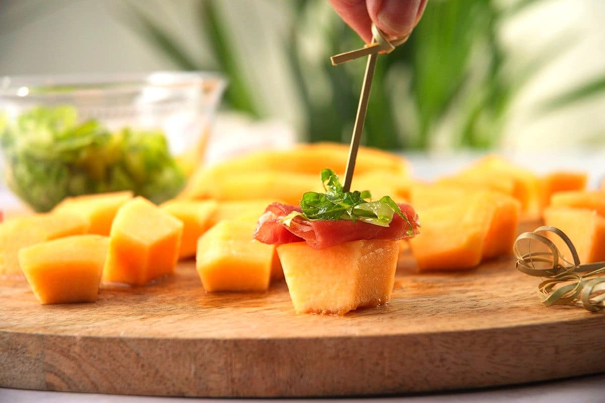 Cantaloupe cube, prosciutto and greens layered with skewer/toothpick.