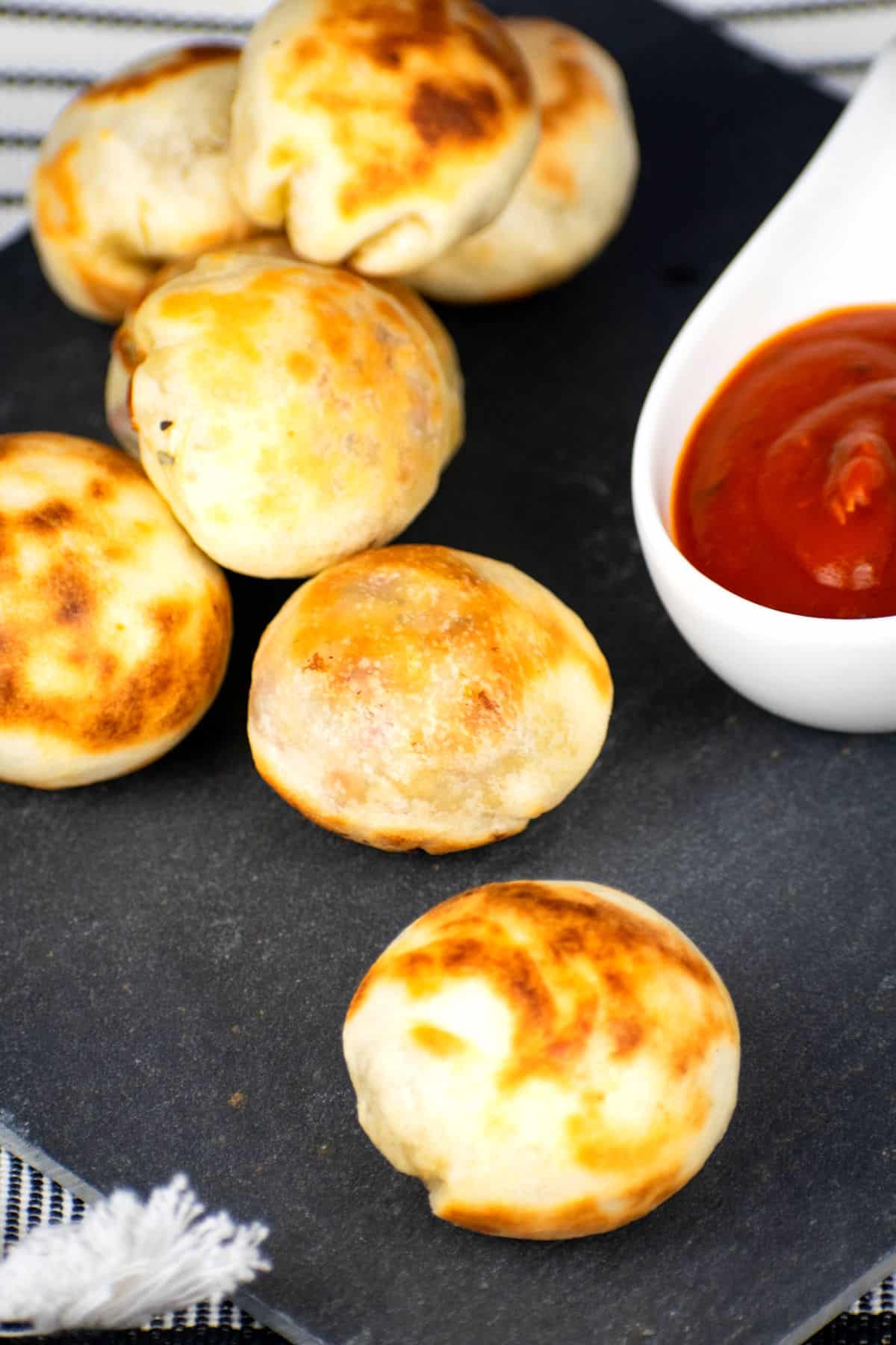 Mini pizza bites on black board with marinara sauce.
