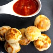 Mini pizza bites on black board with marinara sauce.