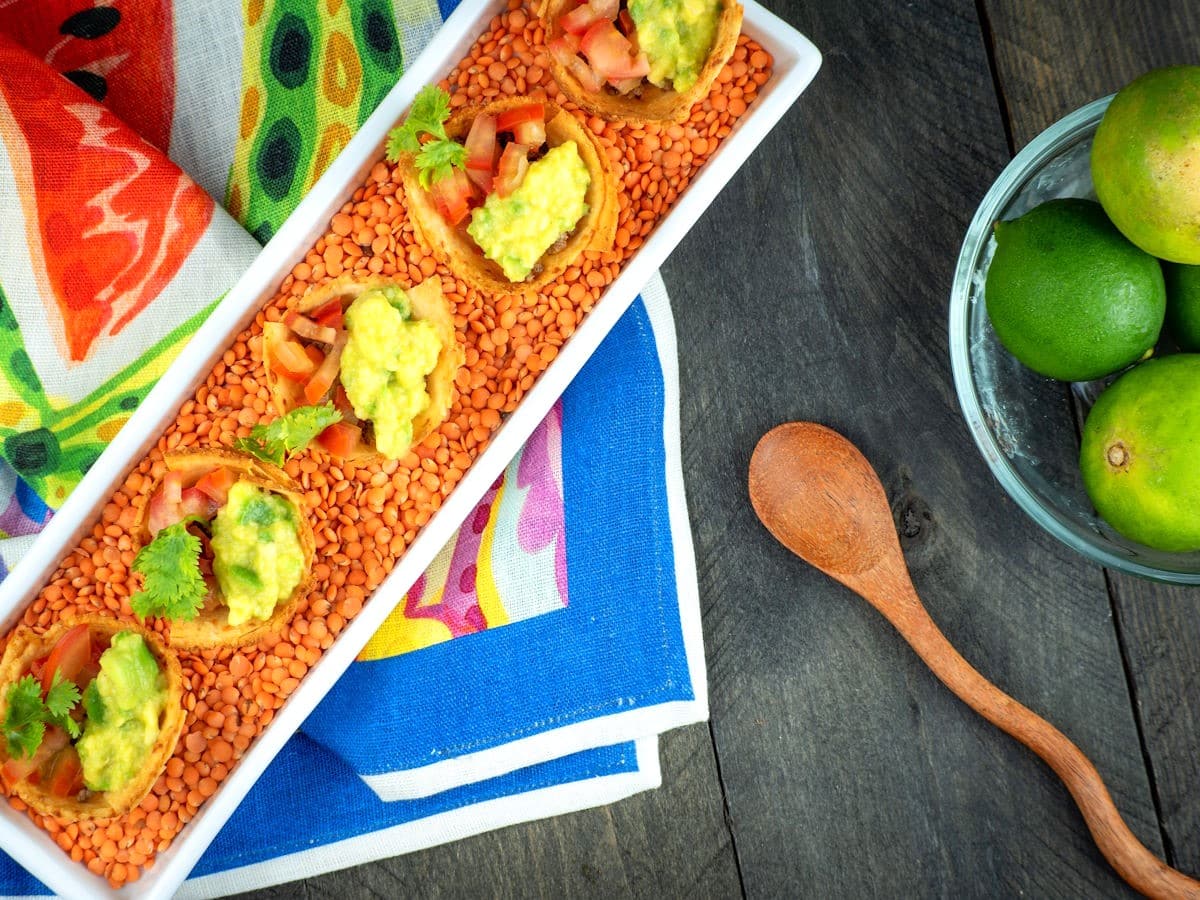 Baked taco cups in white dish on colorful cloth.