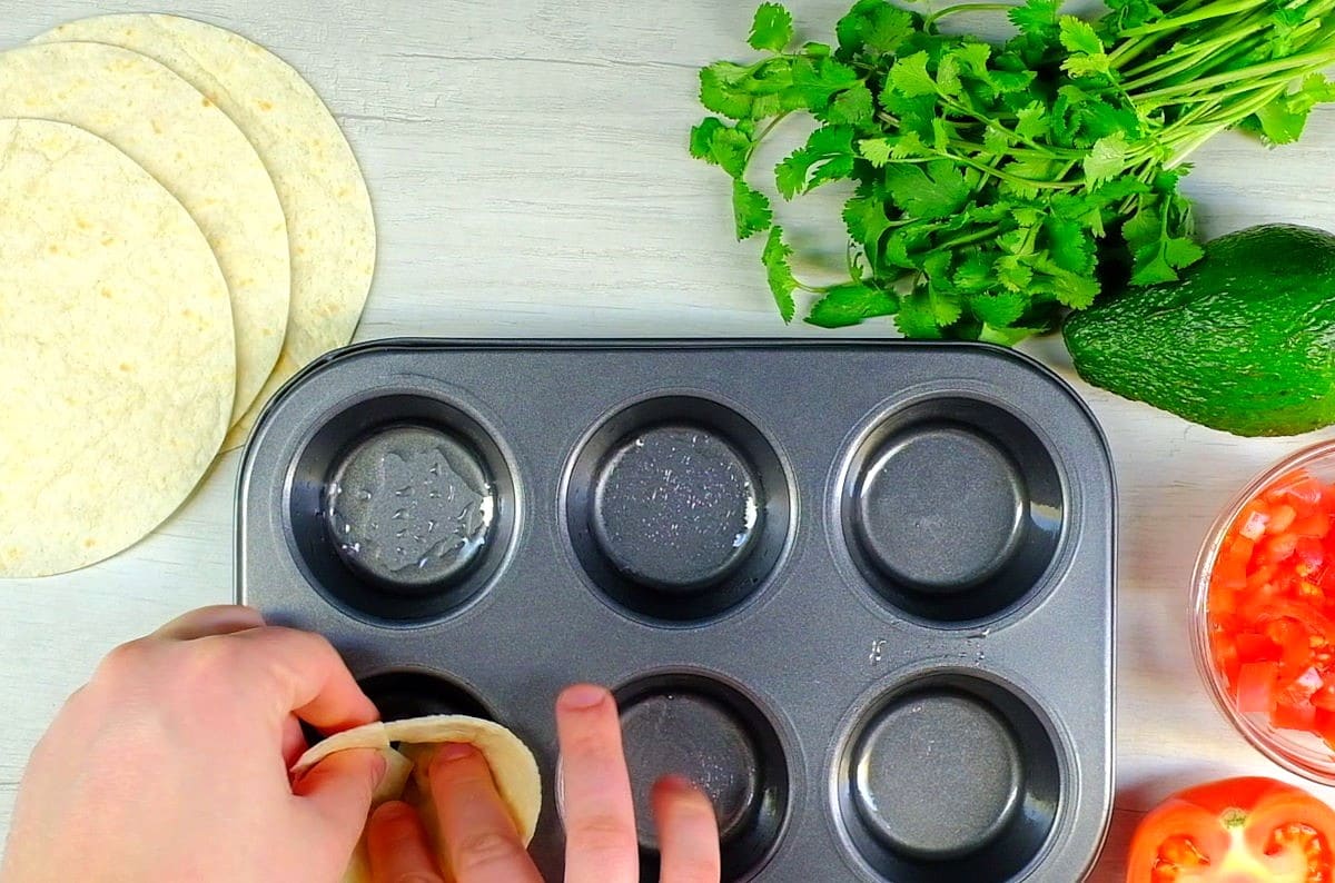 Muffin tin with corn tortillas.
