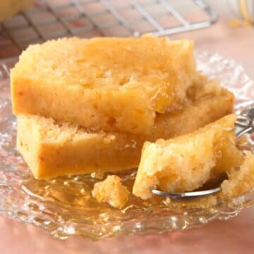 Pancaked bread slices stacked with syrup on small plate.