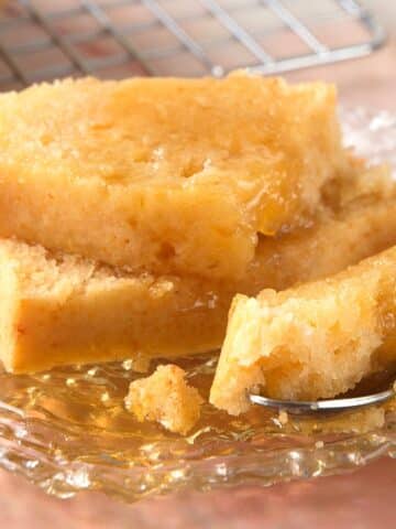 Pancaked bread slices stacked with syrup on small plate.
