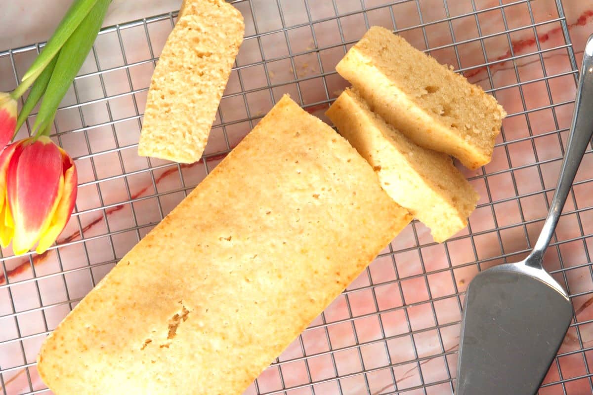 Pancaked bread loaf sliced on baking rack with tulips on the side.