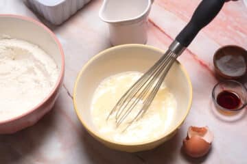 Pancake batter liquid ingredients in bowl with whisk.