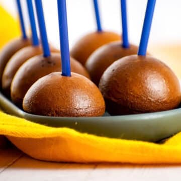 Naked cake pops with blue treat sticks on serving tray.