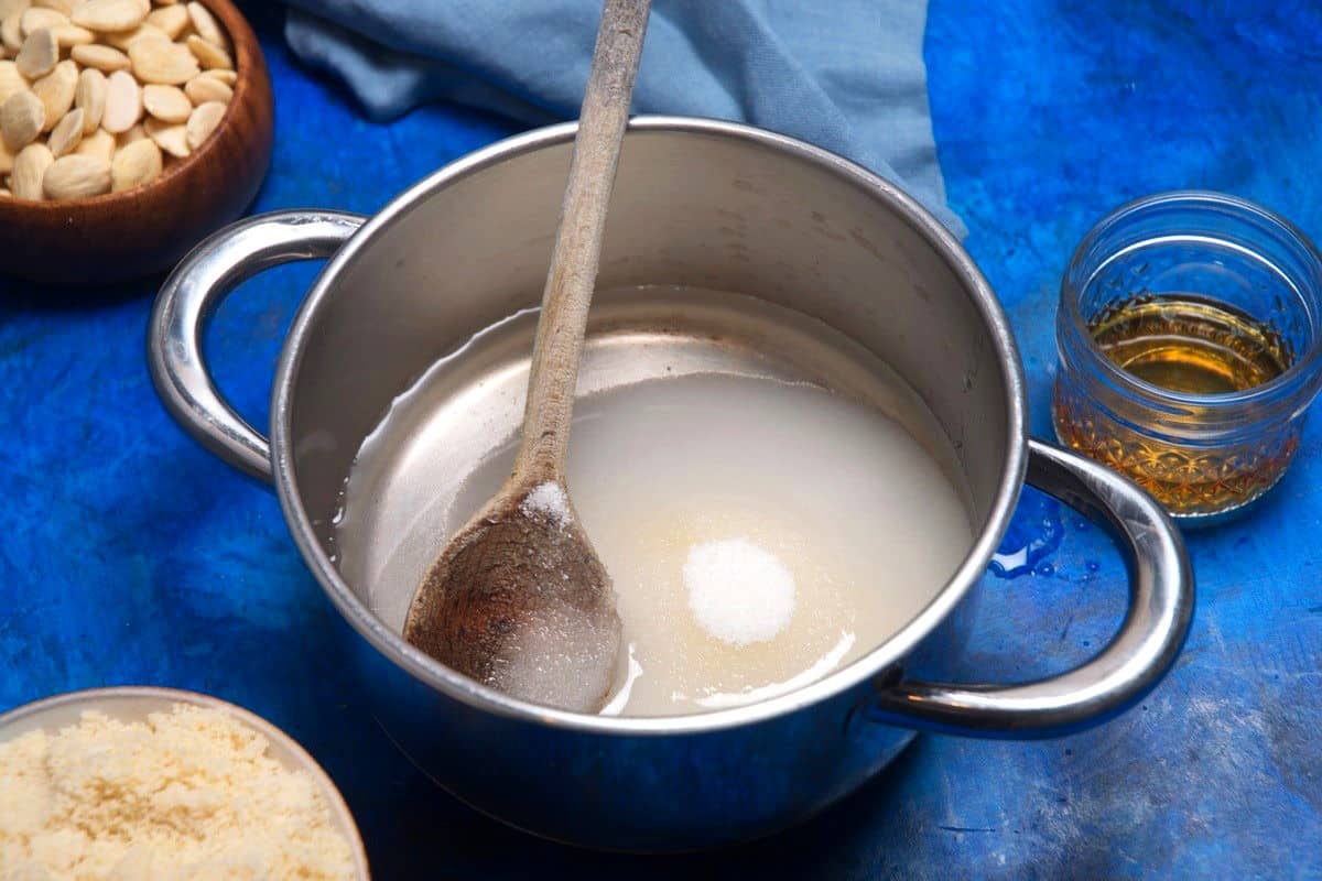 Sugar and water in pot with wooden spoon.