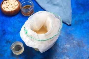 Almond syrup getting filtered through nut milk bag.