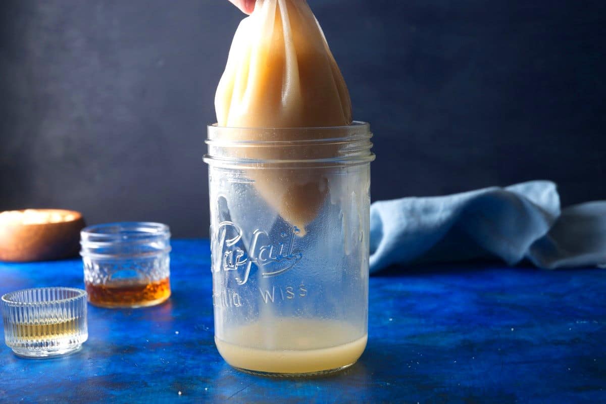 Orgeat almond syrup in nut milk bag over jar.