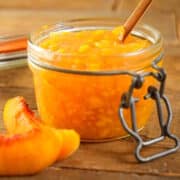 Peach freezer jam in jam jar with the lid off.