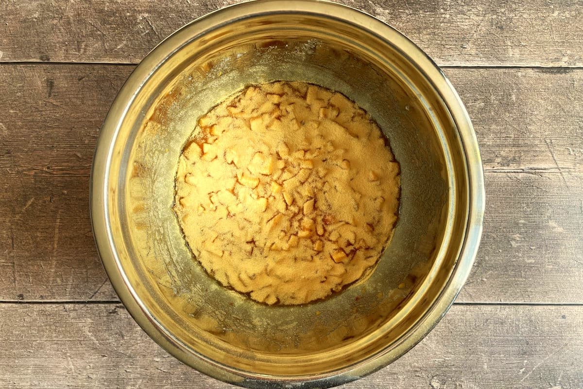Peach jam mixture in bowl with pectin powder.