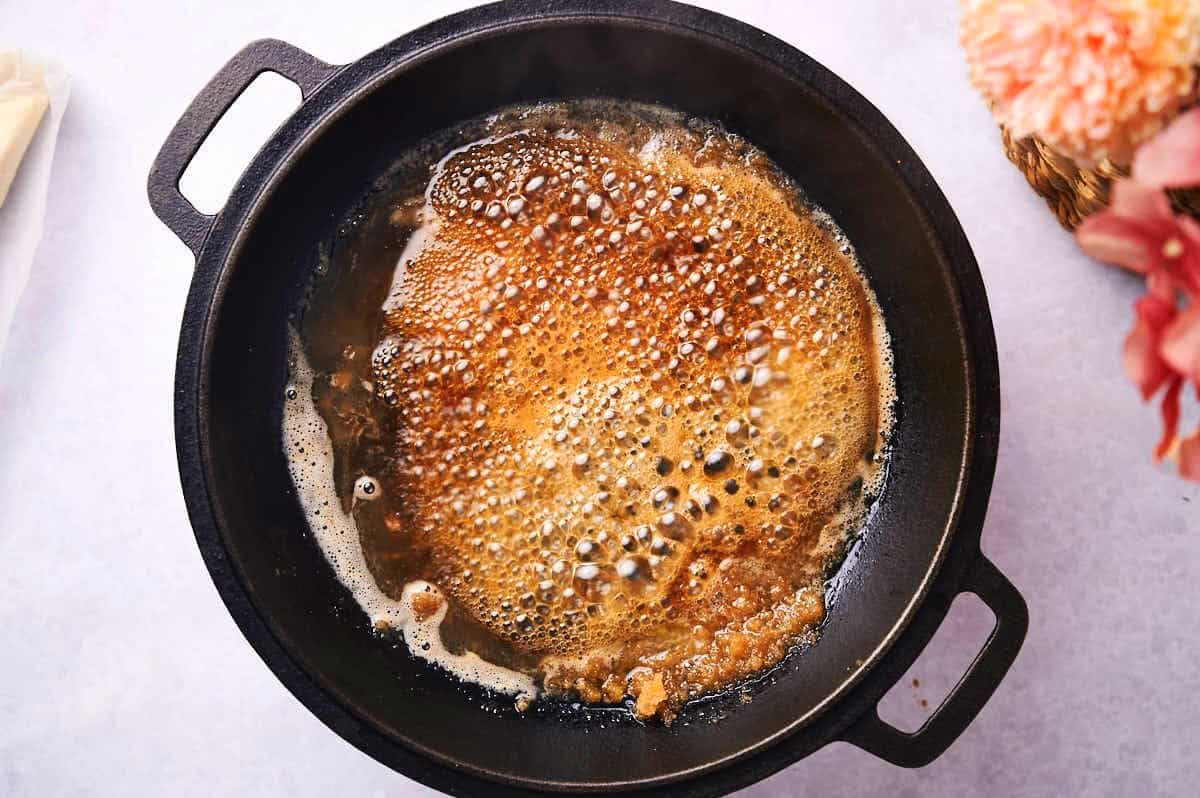 Caramel sauce simmering in cast iron pan.