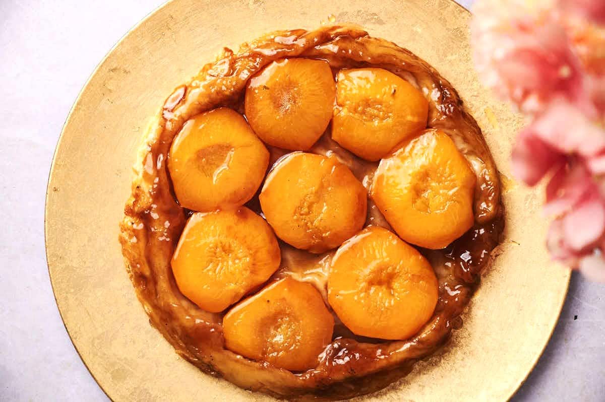 Peach tarte tatin on golden serving tray.