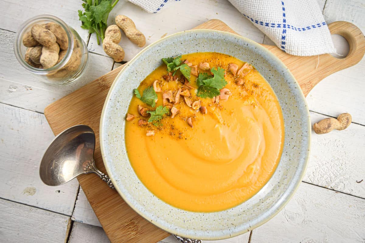 Peanut butter soup in a bowl on wooden board.