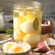 Pickled eggs in jar and sliced open in a bowl.