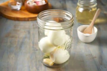 Jar with shelled eggs, garlic and bay leaves.