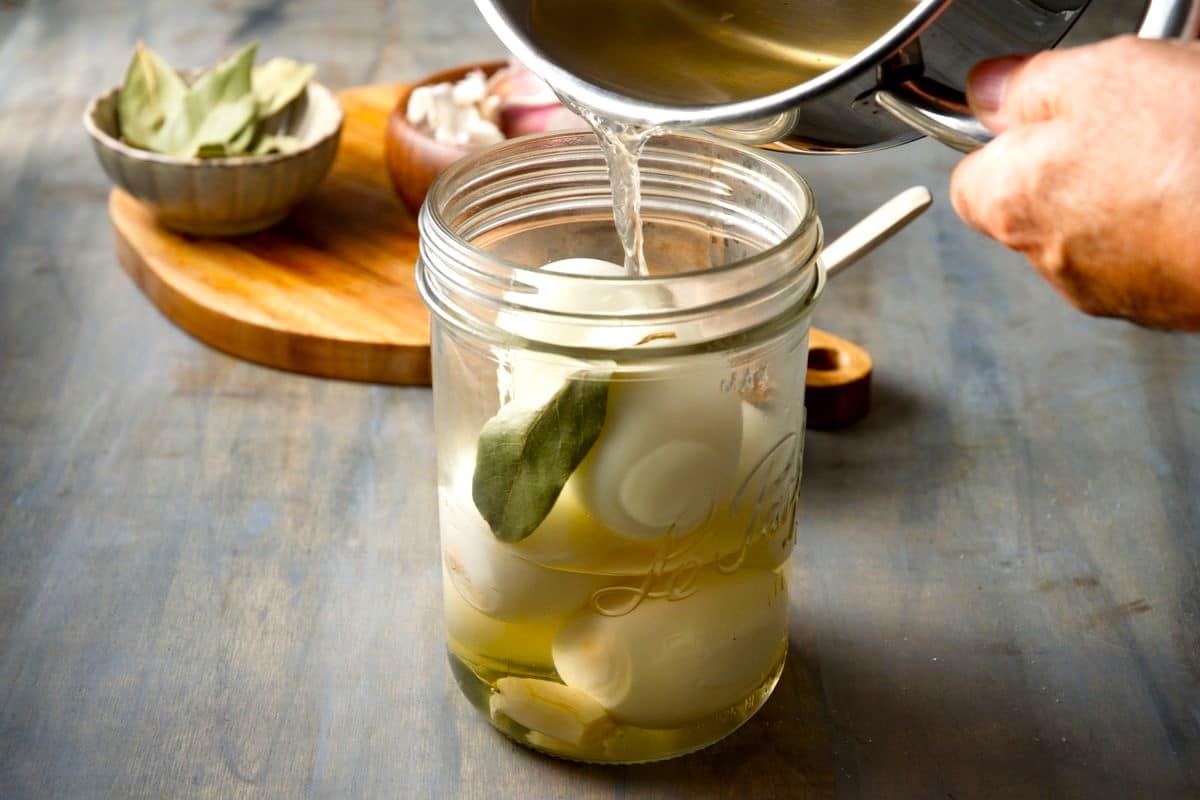 Pickled eggs in a jar with brine pouring into the jar.